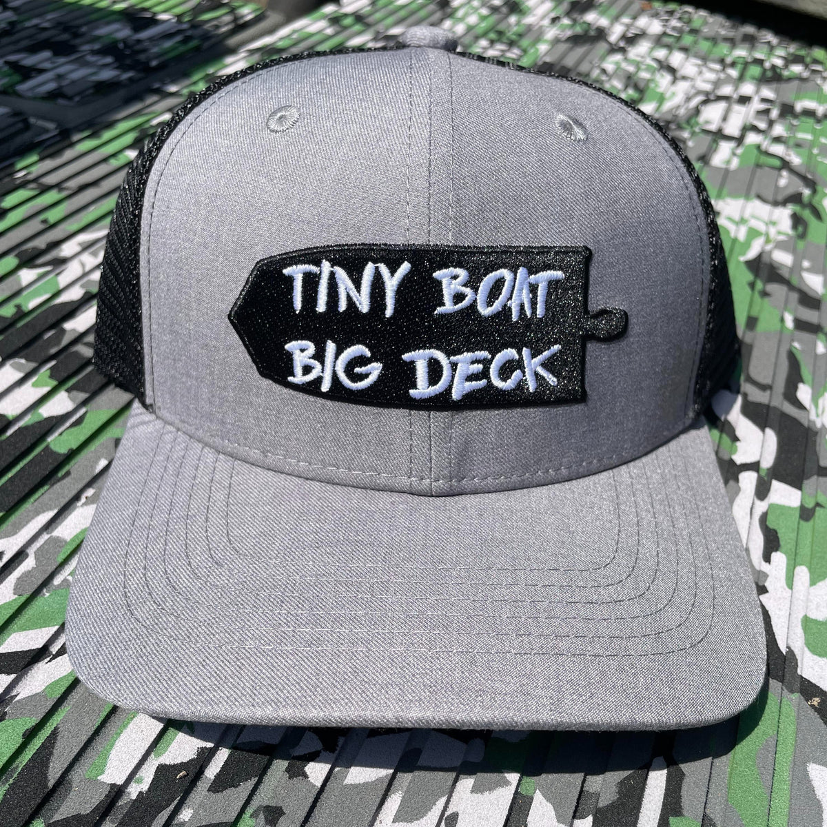Gray trucker hat with black mesh back and "TINY BOAT BIG DECK" patch.