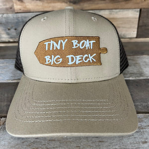 Tan and brown trucker hat with "TINY BOAT BIG DECK" embroidered on a wooden paddle design.