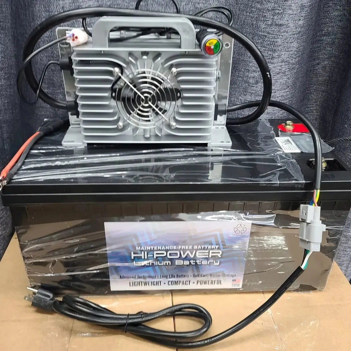 Black Hi-Power 48V lithium battery pack with a silver charger, fan, and cables.