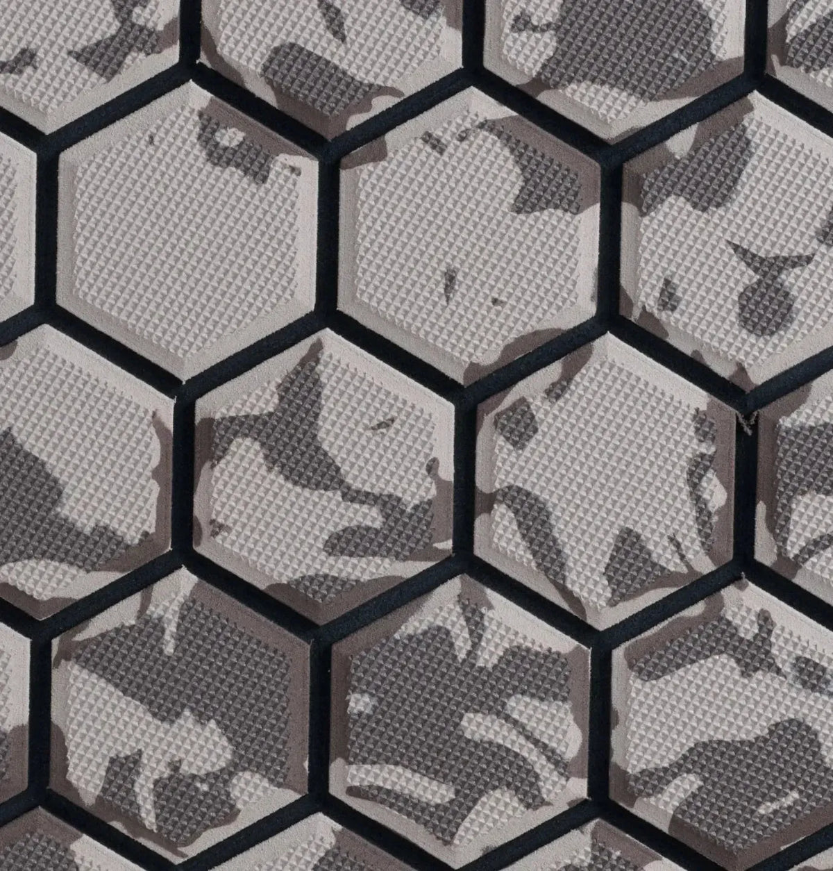 Hexagonal wall tiles with a gray and black camouflage pattern and a textured surface.