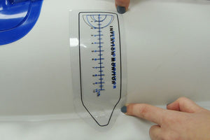 Clear pliable plastic inflation gauge with blue markings, held against a white kayak surface.