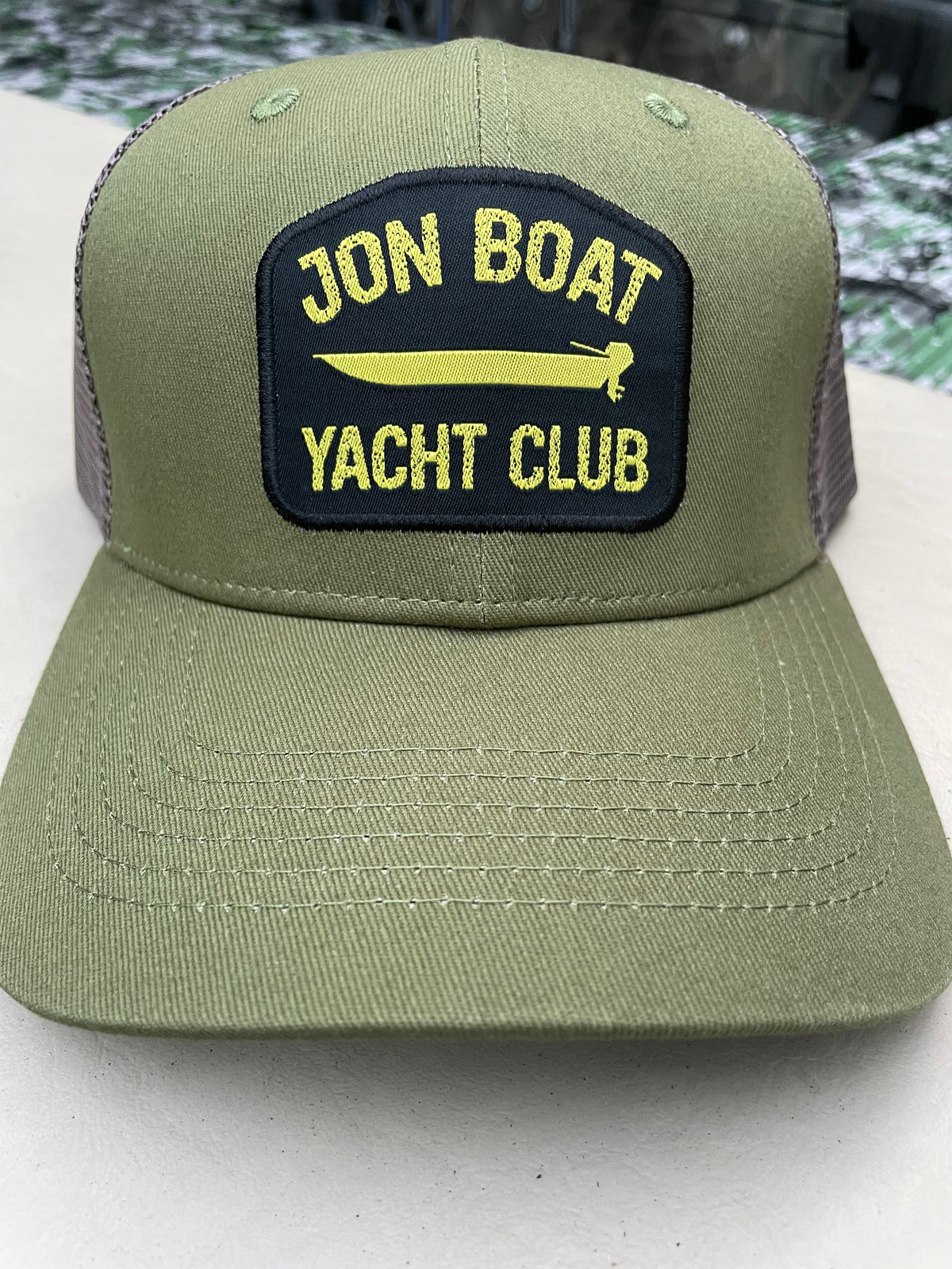 Olive green Jon Boat Yacht Club hat with a black and yellow embroidered patch, featuring a mesh back.