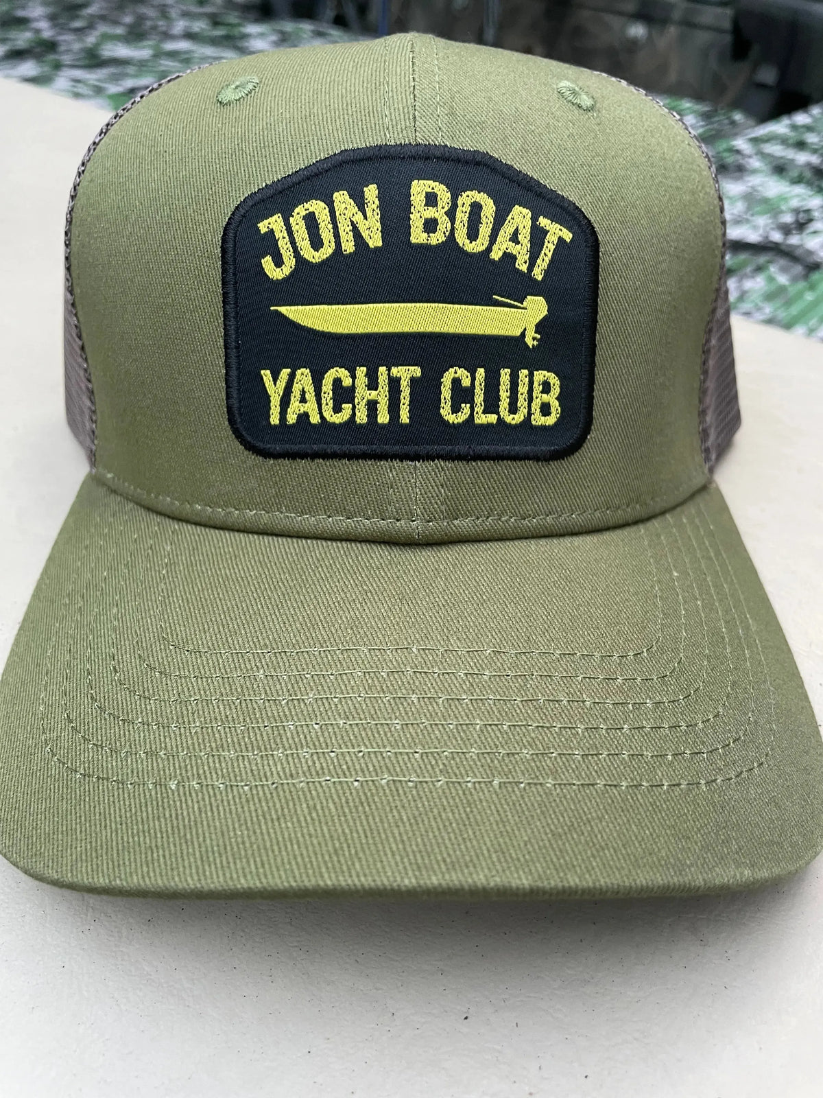 Olive green Jon Boat Yacht Club hat with a black and yellow embroidered patch, featuring a mesh back.