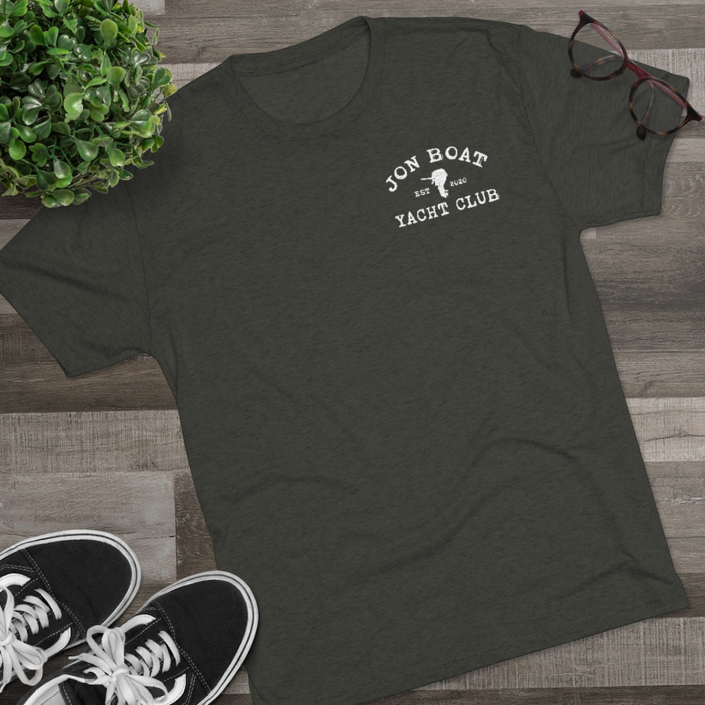 Dark gray tri-blend tee with "Jon Boat Yacht Club" logo, black sneakers, plant, and glasses.
