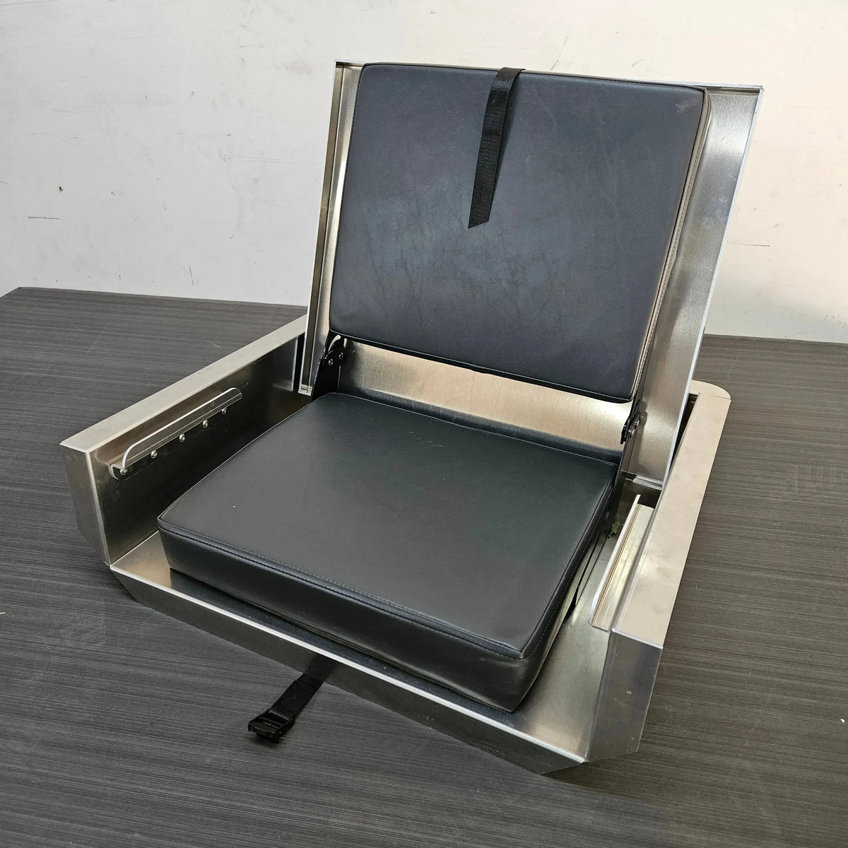 Silver stainless steel flip-up stowable boat seat with black vinyl cushions and a securing strap.