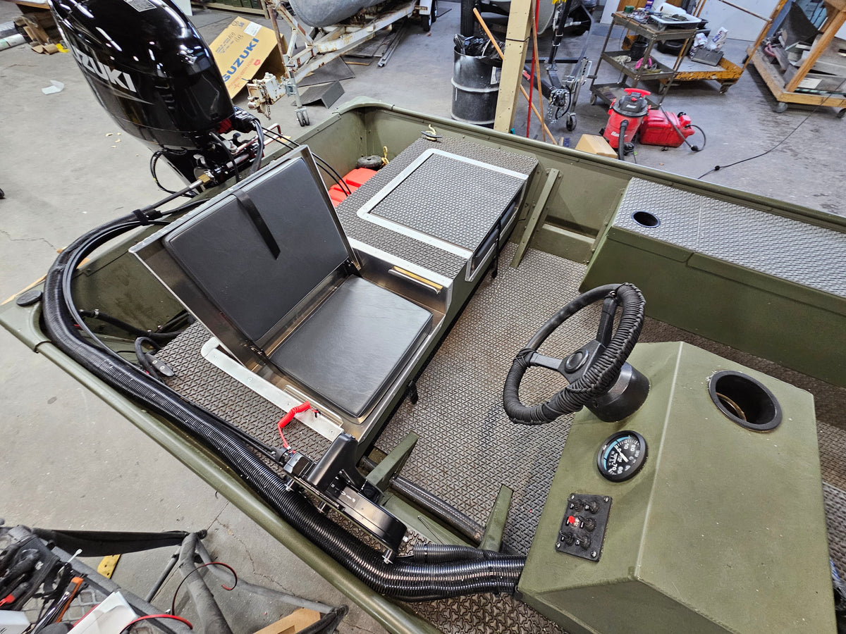 Green boat interior with a black flip-up stowable JumpSeat, steering wheel, and textured deck.