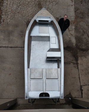 Overhead view of a silver aluminum boat with a man standing beside it, showcasing the DIY drop-in stowable seat design.