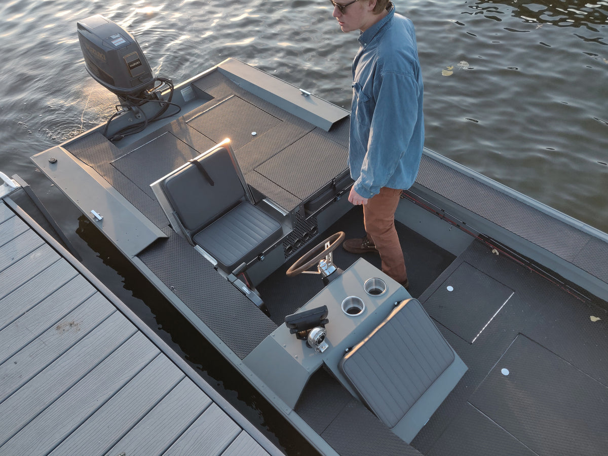 Gray JumpSeat with charcoal vinyl cushions installed in a boat, shown with a man standing nearby.