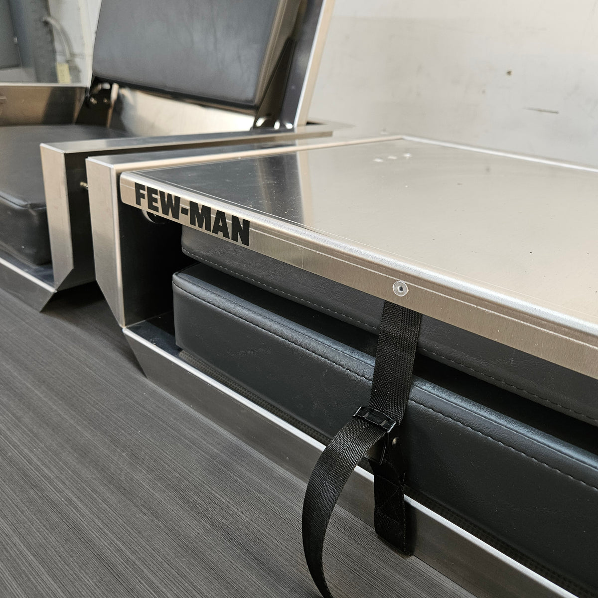 Silver Few-Man JumpSeat, a flip-up stowable boat seat with black vinyl cushions and a cinch strap.