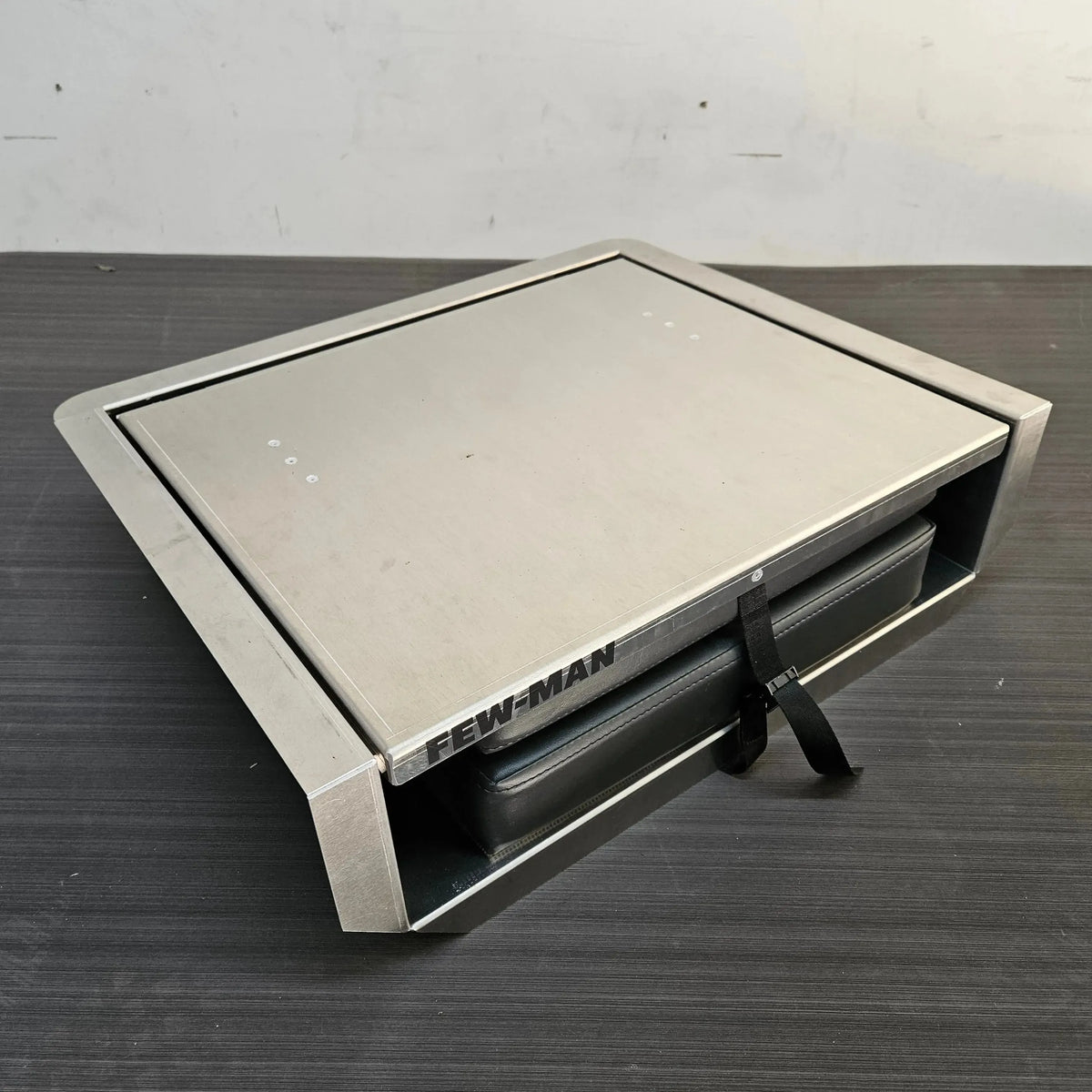 Silver Few-Man JumpSeat, a flip-up stowable boat seat with a black vinyl cushion and cinch strap.