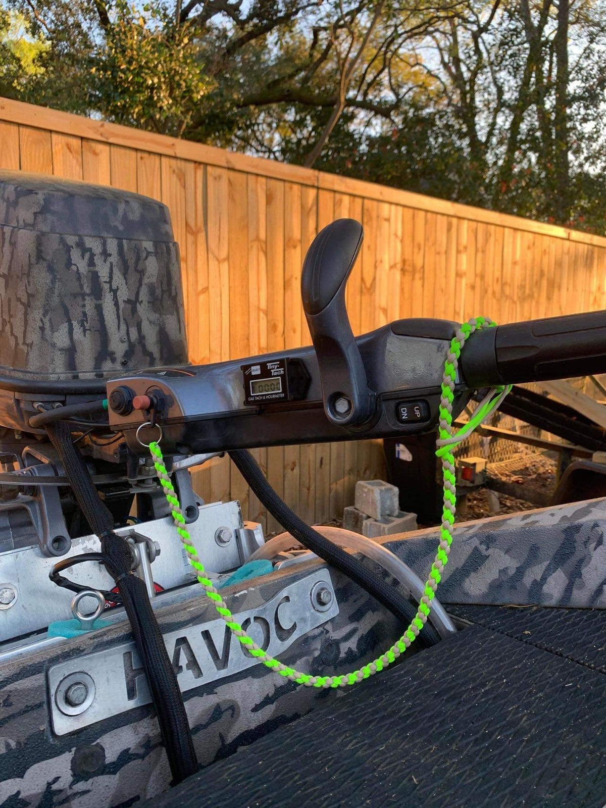 Neon green paracord kill switch lanyard with a metal ring attached to a boat motor.