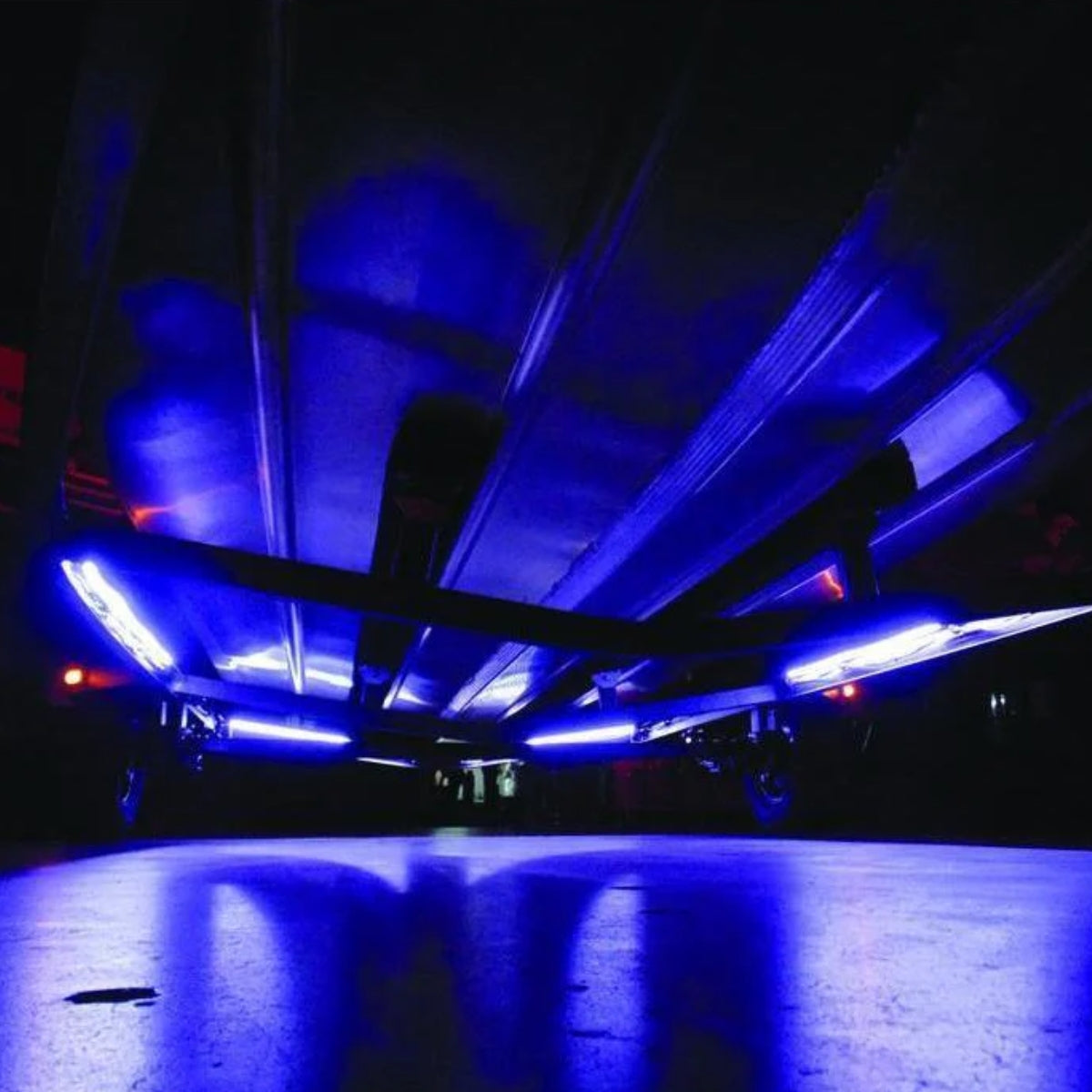 Blue LED flex strip lights illuminating the underside of a trailer at night.