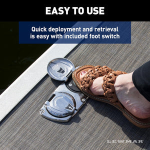 Lewmar Venta electric pontoon anchor winch foot switch on a boat deck, pressed by a foot in a brown sandal.