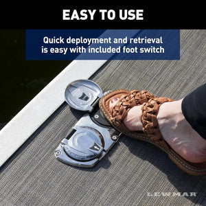 Lewmar Venta electric pontoon anchor winch foot switch on a boat deck, pressed by a foot in a brown sandal.