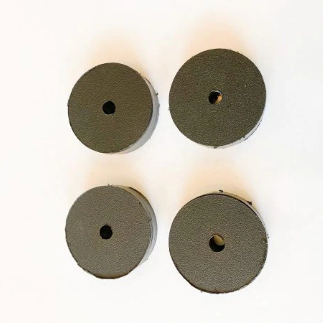 Four dark gray round UHMW motor clamp spacers, 1-inch thick, with a central hole.