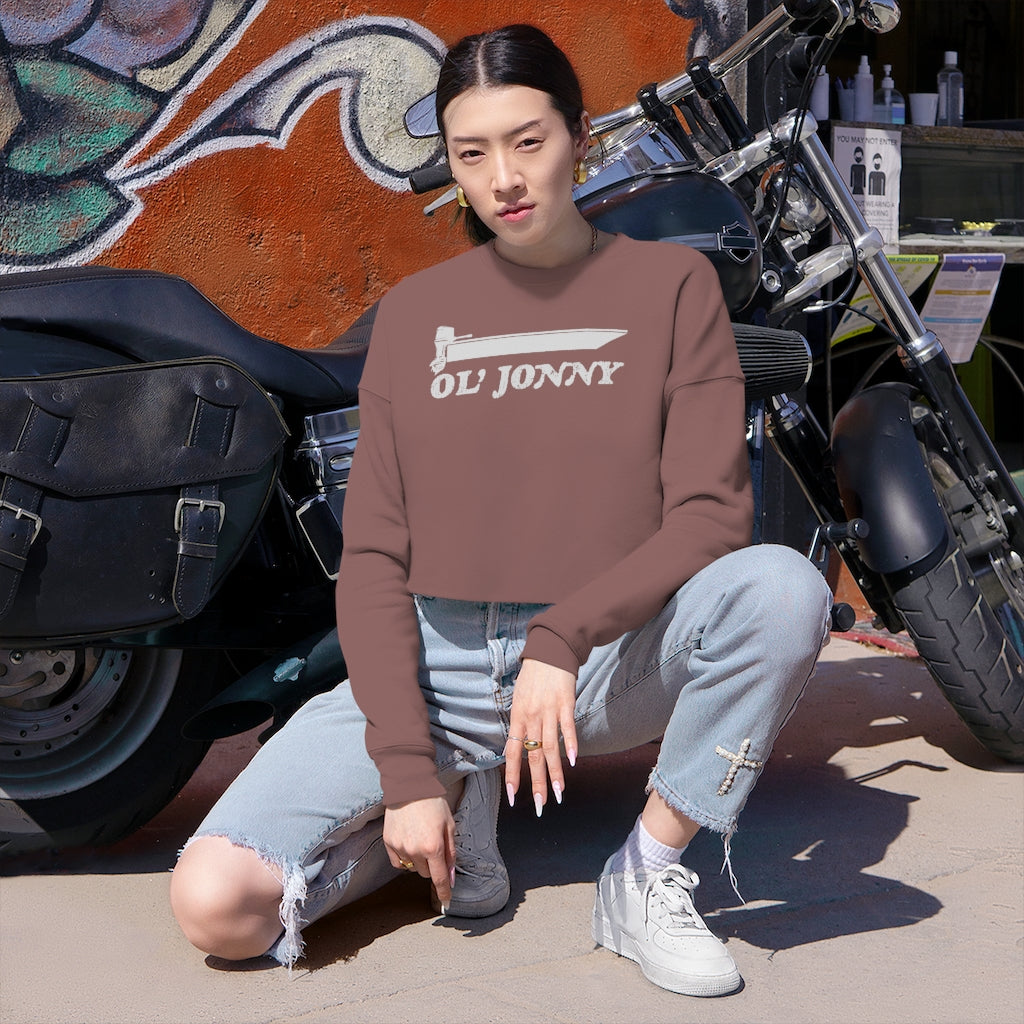 Woman in Ol' Jonny brown cropped sweatshirt, light wash jeans, and white sneakers, next to a motorcycle.