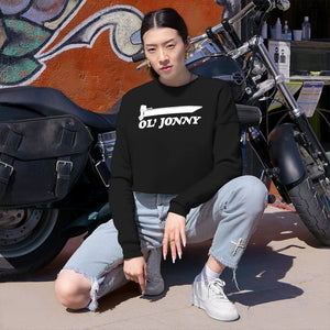 Woman in black Ol' Jonny cropped sweatshirt, light wash ripped jeans, and white sneakers, squatting by a motorcycle.