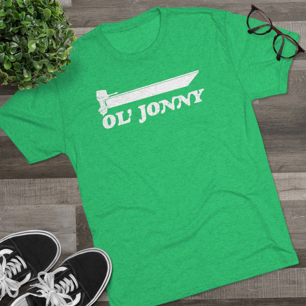 Green tri-blend "Ol' Jonny" regular fit tee with white boat graphic, black sneakers, plant, and glasses.