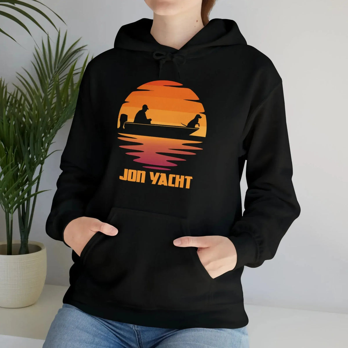 Black Ol Yeller hoodie with a sunset graphic of a person and dog in a boat, "JON YACHT" text.