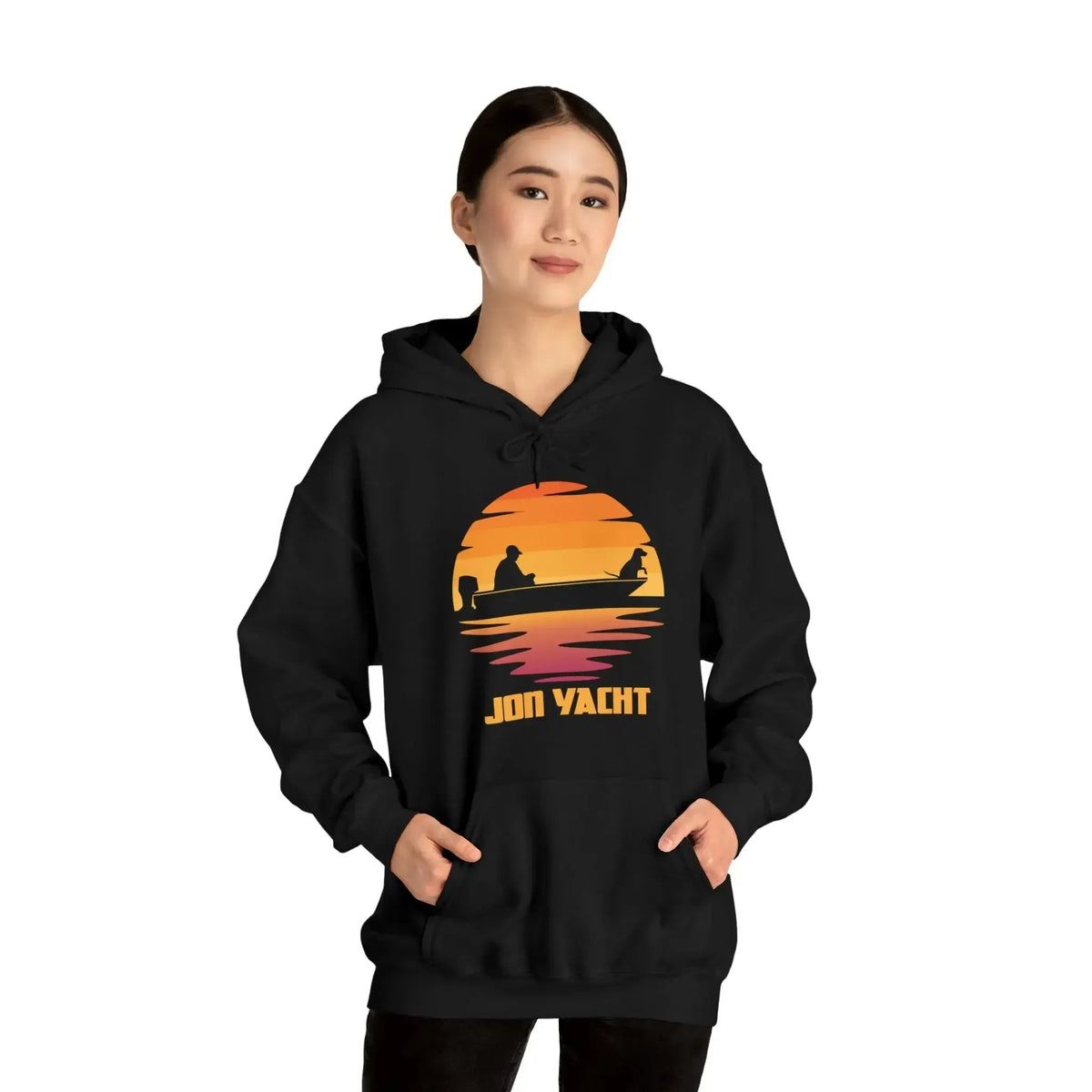 Woman in black hoodie with "Jon Yacht" sunset graphic, kangaroo pocket, and matching drawstring.