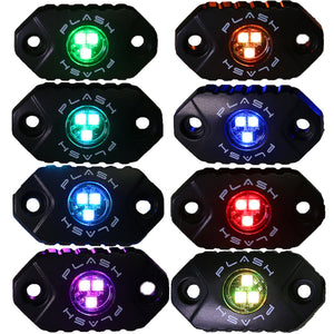 Eight black PlashLights RGB rock lights displaying various colors: green, orange, aqua, blue, light blue, red, purple, and lime green.