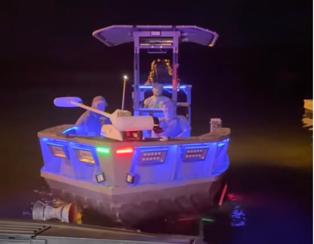 Small boat with blue, red, and green LED lights illuminating its exterior and interior figures.