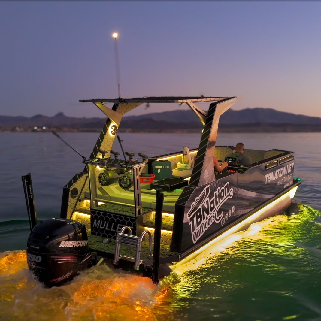 Black boat with yellow Plashlights EPIK underwater transom lights glowing in the water at dusk.