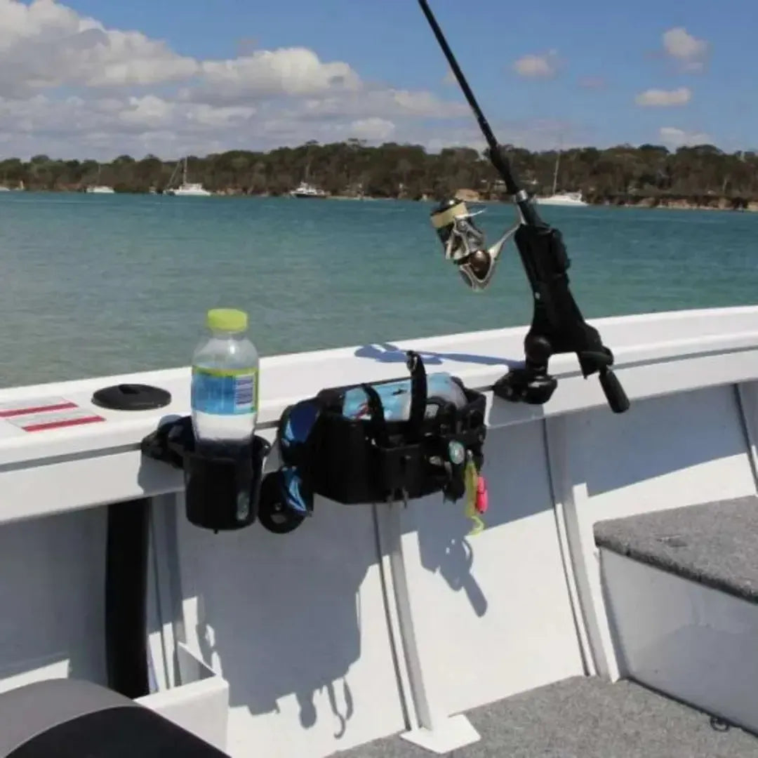Black Railblaza Track Mount Tackle Caddy with a drink holder and fishing rod attached to a white boat gunnel.