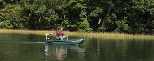 Man fishing from a Hunter Green Sea Eagle 285 Frameless Pontoon Boat with a trolling motor on a calm lake.