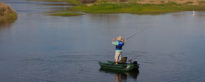 Man fly fishing from a compact Hunter Green Sea Eagle 285 frameless inflatable pontoon boat on a calm lake.