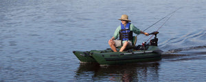 Man in a straw hat and life vest fishing from a green Sea Eagle 285 Frameless Pontoon Boat on calm water.