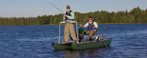 Two men fishing from a dark hunter green Sea Eagle 375fc FoldCat inflatable pontoon boat on a lake.