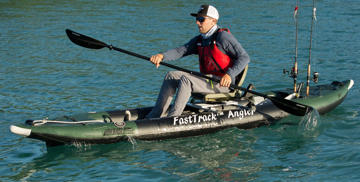 Man paddling a green and black Sea Eagle 385fta FastTrack Angler inflatable kayak with fishing rods.
