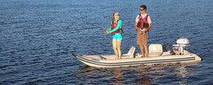 Two people fishing from a tan Sea Eagle 437ps PaddleSki inflatable catamaran with a Honda motor.