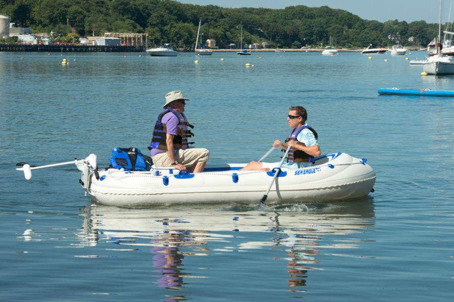 Two men in an inflatable Sea Eagle boat on water, one rowing with a 5' two-part oar.