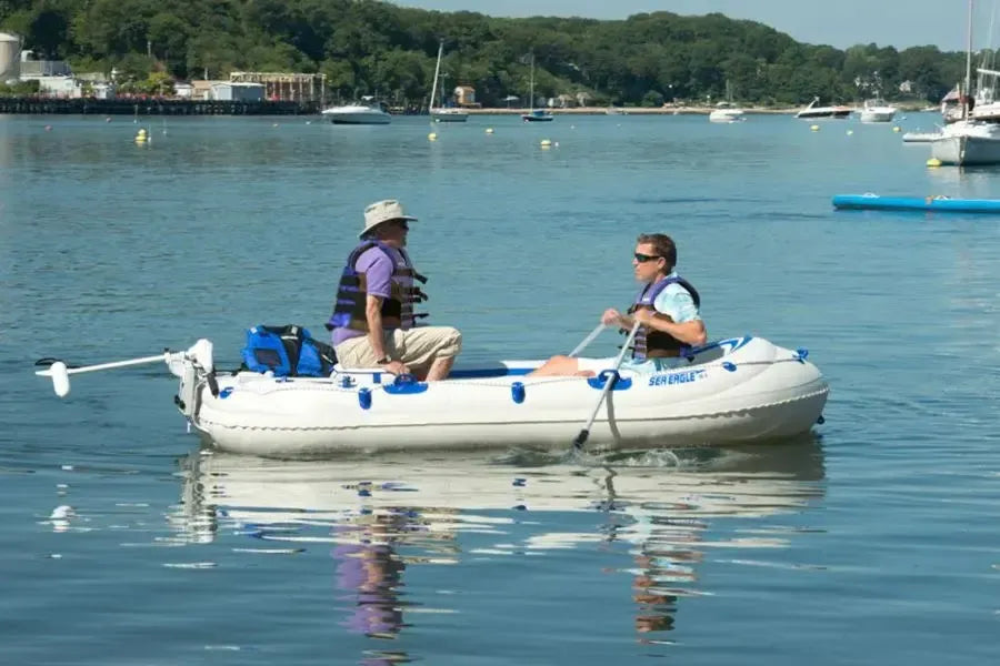 Two men in an inflatable Sea Eagle boat on water, one rowing with a 5' two-part oar.