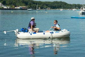 Two men in an inflatable Sea Eagle boat on water, one rowing with a 5' two-part oar.