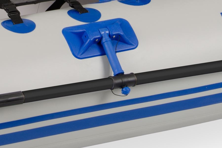 Black oar attached to a white inflatable boat with blue stripes and a blue oarlock.
