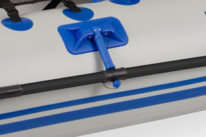 Black oar attached to a white inflatable boat with blue stripes and a blue oarlock.