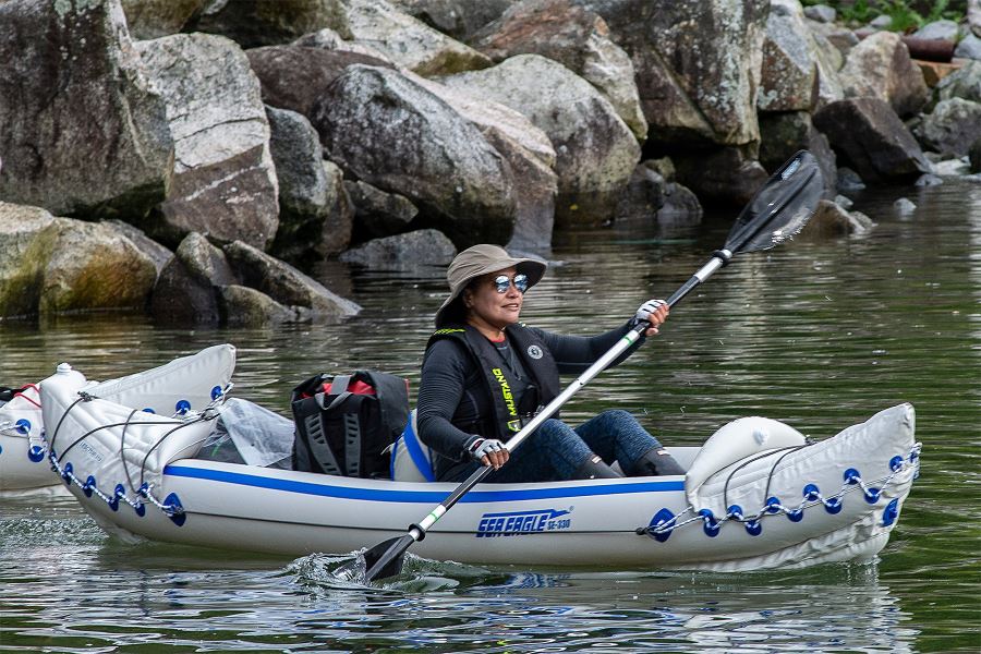 Woman in a Sea Eagle inflatable kayak paddles with a black and silver AB30 4-part paddle.