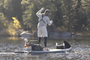 Man paddling a Sea Eagle SUP with a black composite paddle on a calm lake.