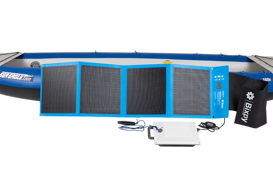 Blue Bixpy 80W solar panel, white K-1 motor, and black storage bag in front of a blue Sea Eagle kayak.
