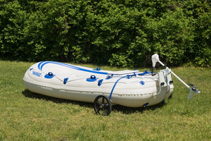 White Sea Eagle inflatable boat with blue stripes, an attached EZ Cart (wide) wheel, and a mounted trolling motor on green grass.