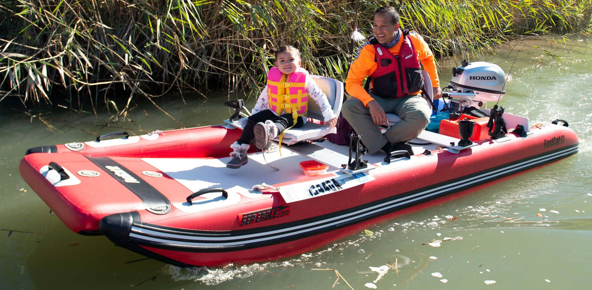 Red Sea Eagle FastCat12 inflatable catamaran with a man and child, Honda motor, on a river.