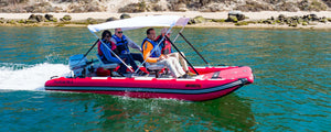 Red Sea Eagle FastCat14 inflatable catamaran with four people, a white bimini top, and Honda outboard motor on water.