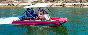 Red Sea Eagle FastCat14 inflatable catamaran with four people, a white bimini top, and Honda outboard motor on water.