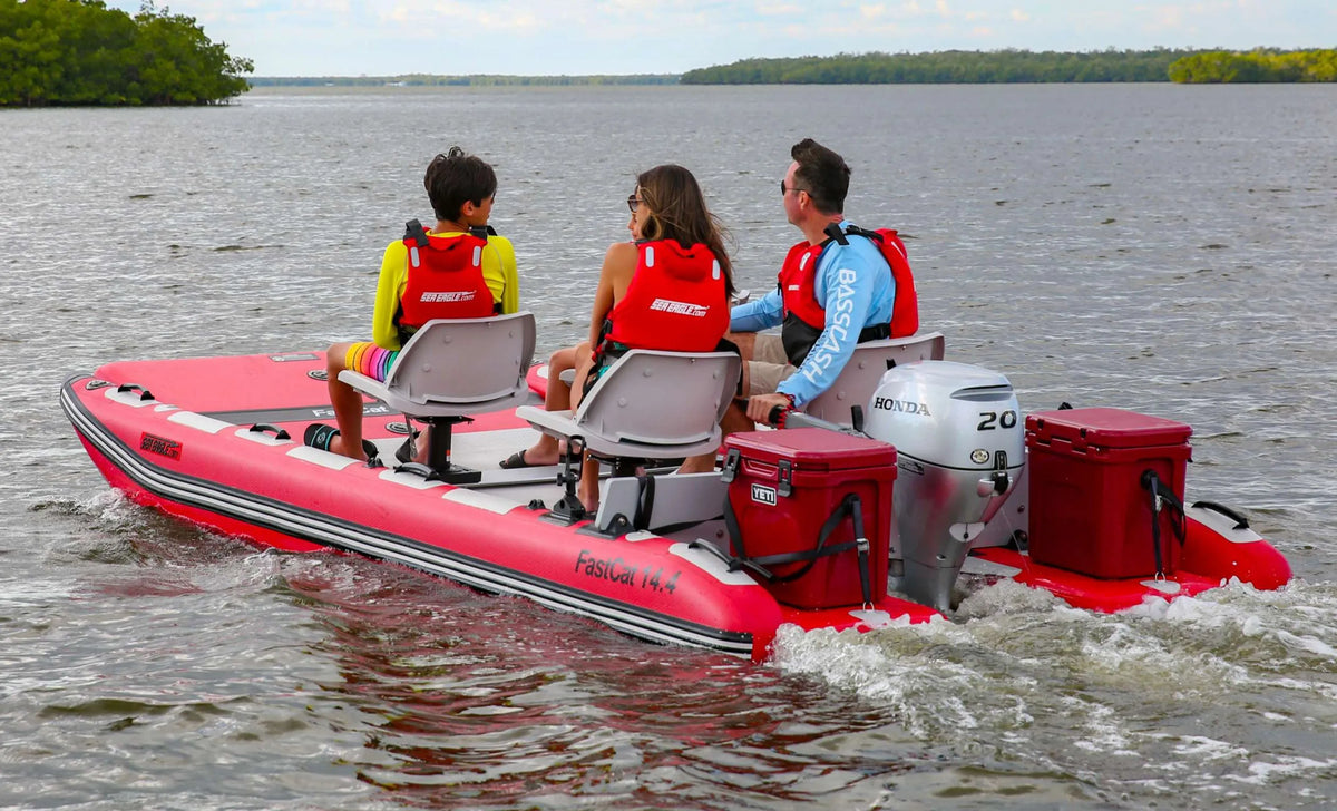 Red Sea Eagle FastCat14 inflatable catamaran with three people, an outboard motor, and two red coolers on the water.