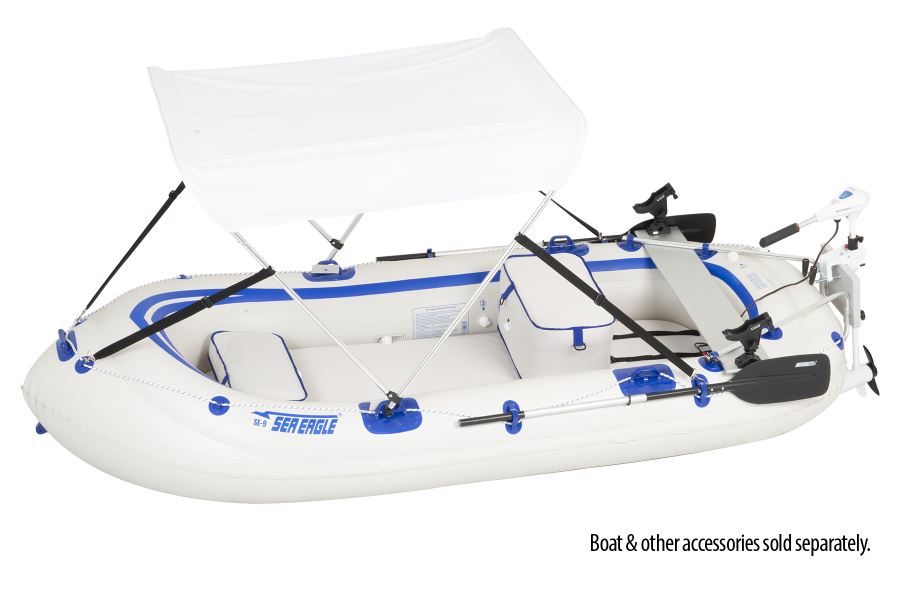 White inflatable Sea Eagle boat with blue trim, a white sun canopy, trolling motor, and fishing rod holders.