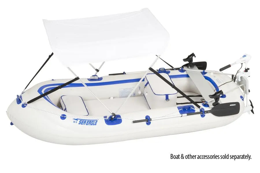 White inflatable Sea Eagle boat with blue trim, a white sun canopy, trolling motor, and fishing rod holders.
