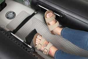 Feet in sandals resting on black Sea Eagle FlexBrace adjustable footrests inside a gray and green inflatable kayak.